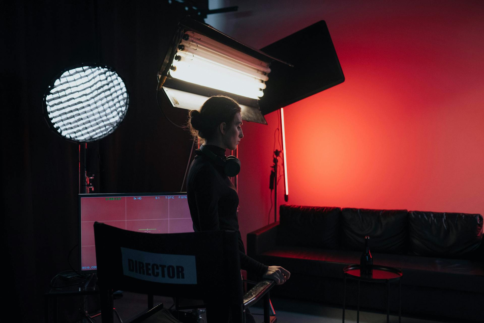 A director in a studio setting with lighting and equipment, creating a cinematic atmosphere.