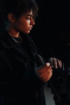 A professional female cinematographer focusing on camera operation in a dark setting.