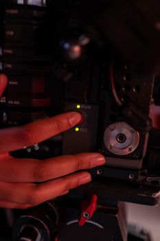 A close-up shot of hands pressing buttons on a professional camera in dim lighting.