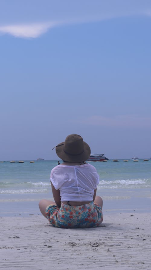 Free Photo of Woman Sitting On Seashore Under A Blue Sky Stock Photo