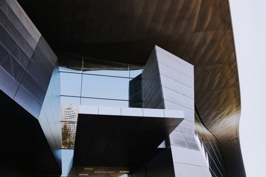 Low angle shot of a modern, futuristic building with geometric glass panels in Munich.