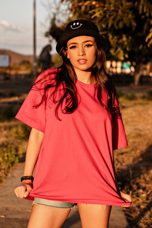 Woman In Red T-Shirt With Black Hat and Denim Shorts