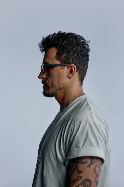 Focused profile portrait of a man in glasses against a white background.
