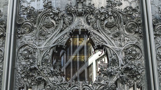 Close-up of an ornate gothic facade featuring detailed iron carvings and a glass window.