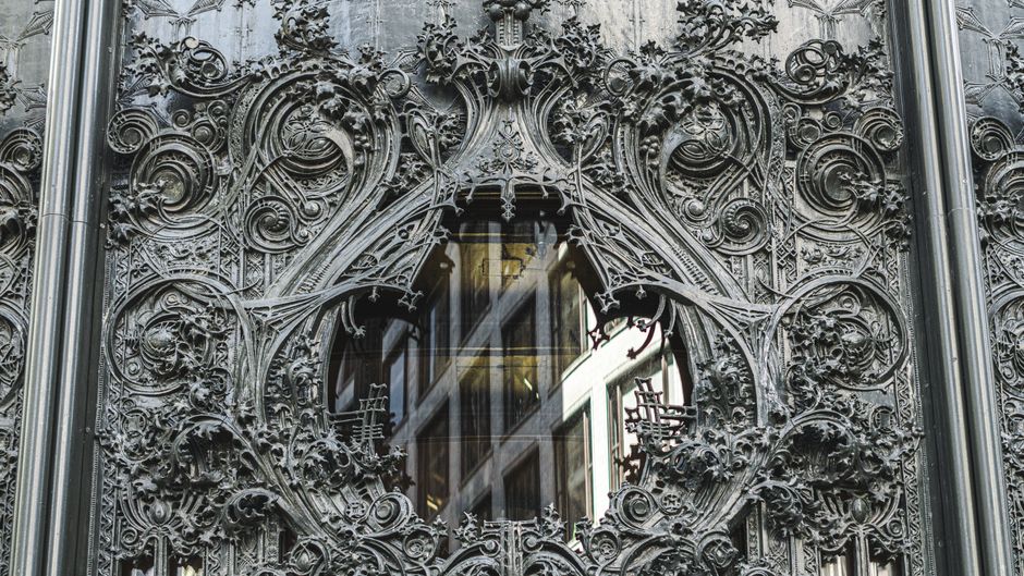 Close-up of an ornate gothic facade featuring detailed iron carvings and a glass window.