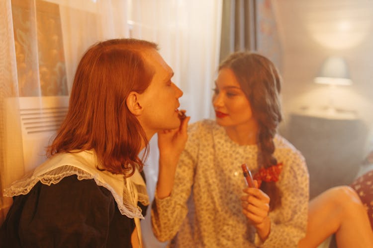 A Woman Applying Lipstick To A Person