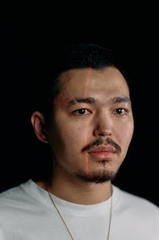 Studio portrait of a man with laser grid lines for facial recognition on a black background.