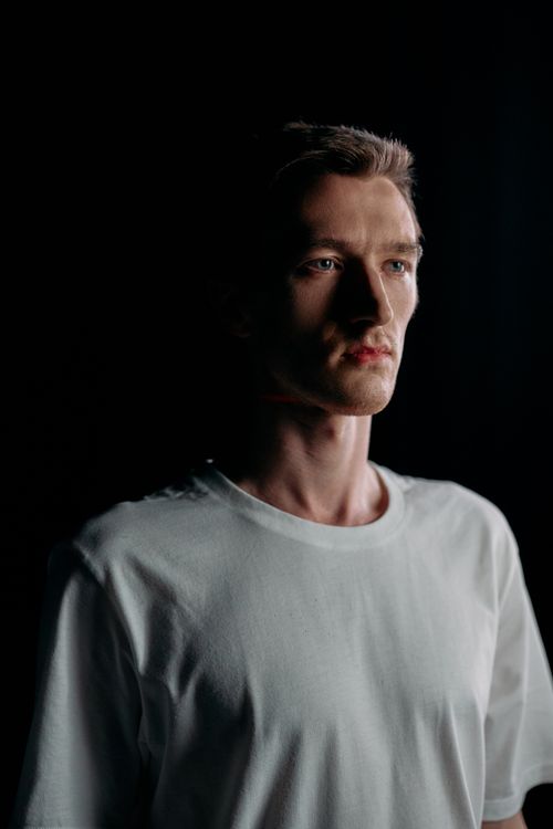 Free Dramatic studio portrait of an adult man in low-key lighting with a contemplative expression. Stock Photo