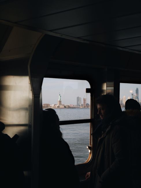 Silhouetted ferry passengers with the Statue of Liberty view in New York City.