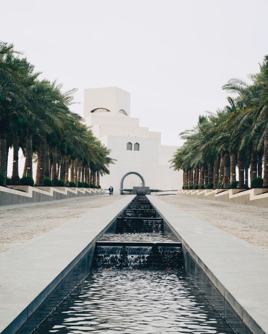 Stunning view of the Museum of Islamic Art in Doha, lined with palm trees and a canal.