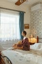 Woman in Red and Black Floral Dress Sitting on Bed