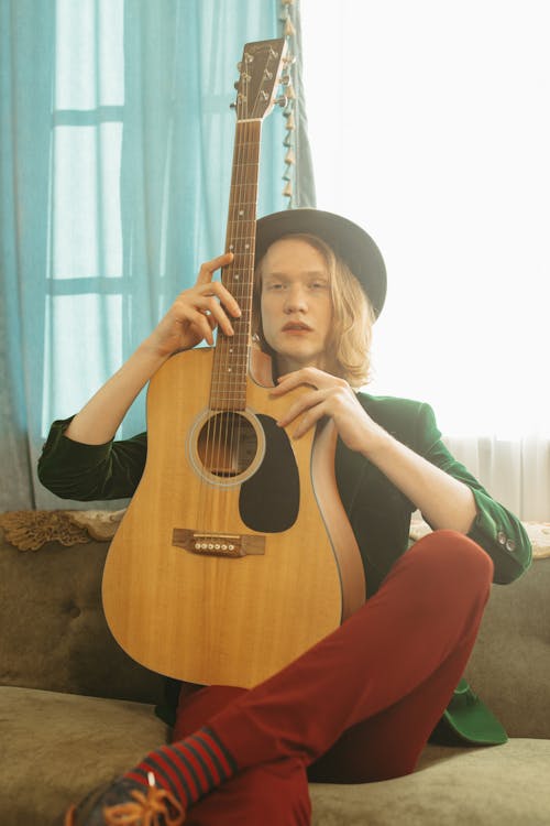 Man in Green Blazer Holding Brown Acoustic Guitar