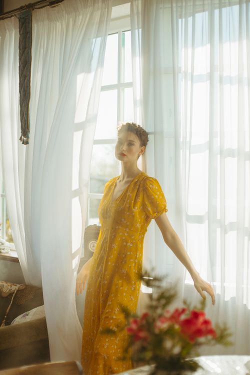 Free Soft sunlight filters through curtains, enveloping a woman in a peaceful, warm ambiance. Stock Photo
