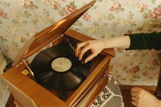 Hand playing a vinyl record on a vintage turntable in a retro styled room.