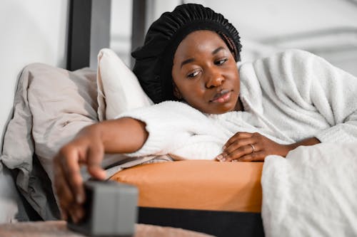 Free Woman in Bed Switching Alarm Clock Off Stock Photo