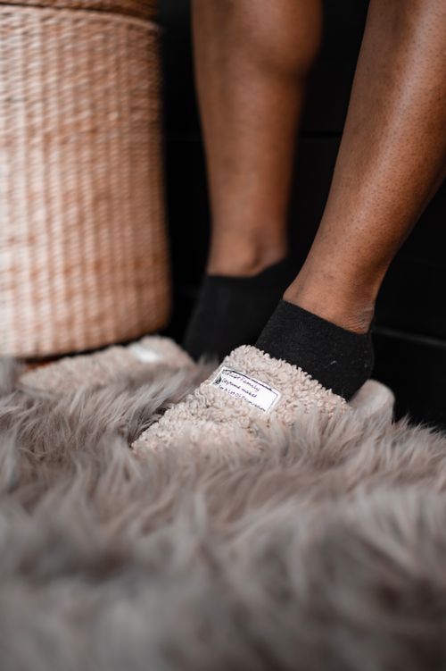 Free Close-up of legs in cozy slippers on a soft rug indoors. Stock Photo