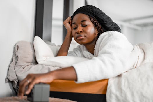 A woman in a cozy white robe turns off her alarm clock for a slow morning.