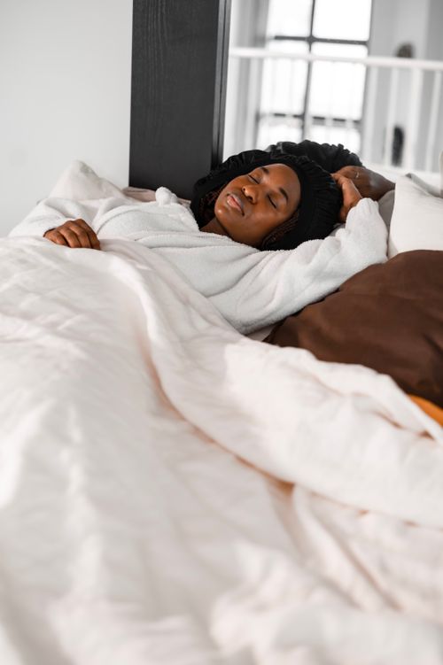 Free A young woman enjoying a restful sleep in a cozy bedroom setting. Stock Photo