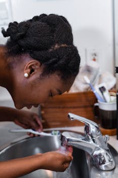 Close-up of a woman washing toothbrush at the sink, focusing on personal hygiene.