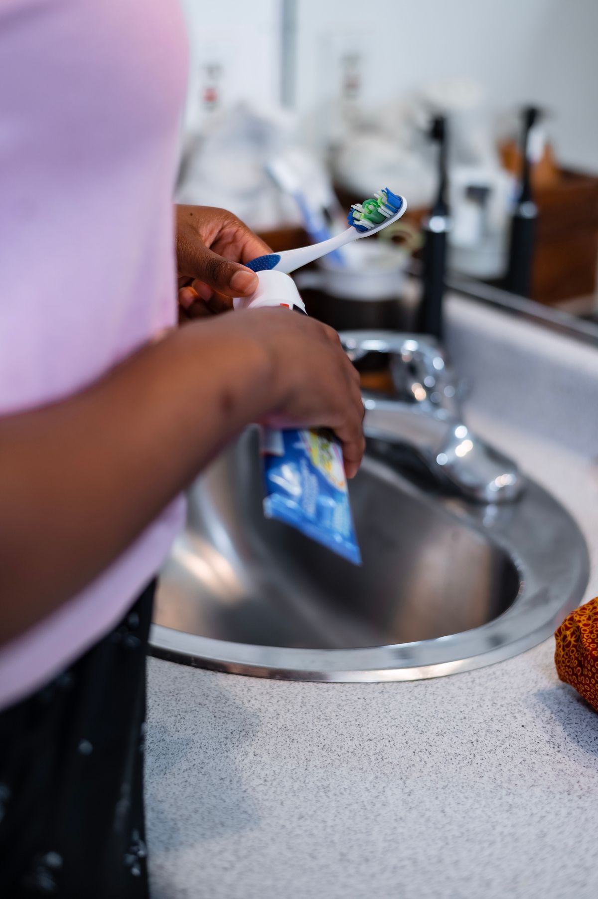 Person holding an electric toothbrush next to a bathroom sink