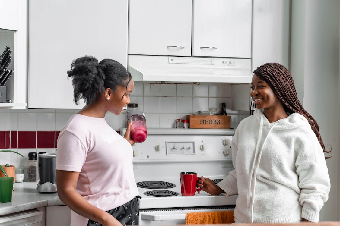Free Women Talking to Each Other While in the Kitchen Stock Photo