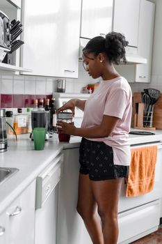 A woman prepares a fresh smoothie at home in a modern kitchen setting.