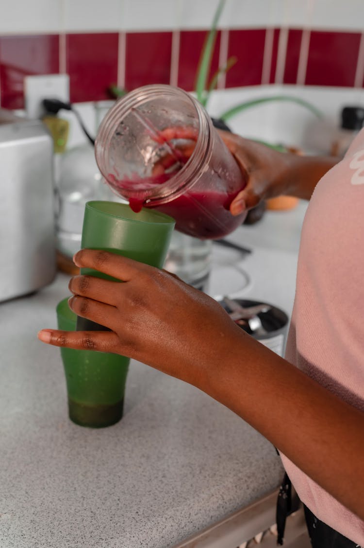 A Hand Pouring Shake On The Plastic Glass