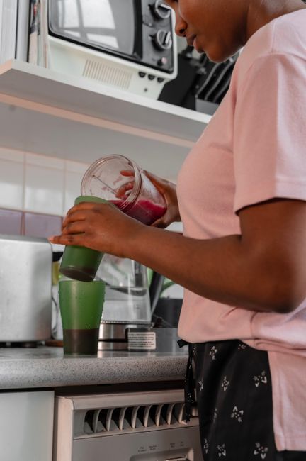 African American woman making a green smoothie in a modern kitchen setting.
