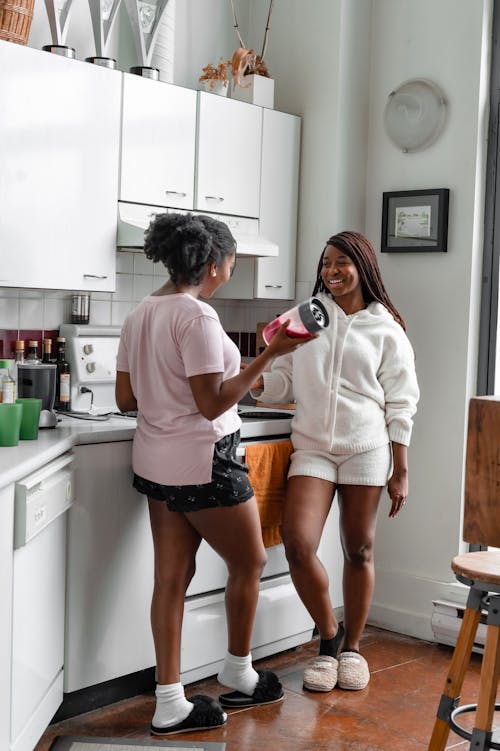Free Women Standing in the Kitchen while Having a Concersation Stock Photo