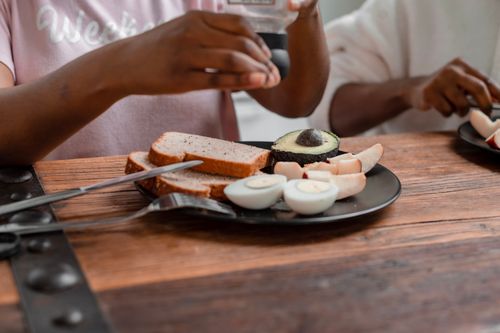 Free A wholesome breakfast plate featuring avocado, boiled eggs, and bread on a wooden table. Stock Photo