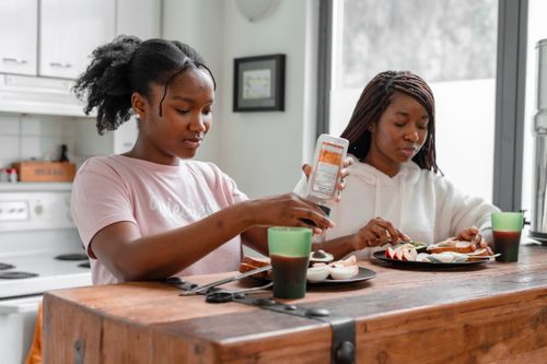 Free Two women having breakfast at a wooden kitchen table with drinks. Stock Photo