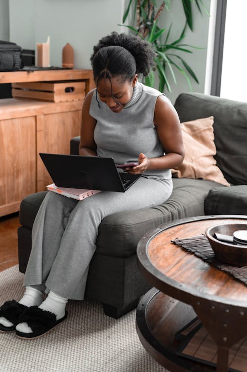 A Woman Using a Laptop While sitting on a Couch