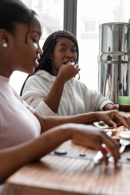 Free Two black women are enjoying a meal together indoors, focusing on friendship and cuisine. Stock Photo