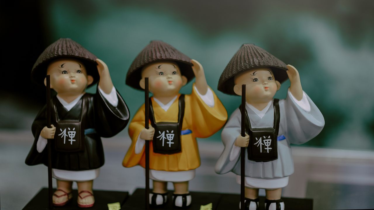 three playful figurines of zen monks in colorful traditional outfits c