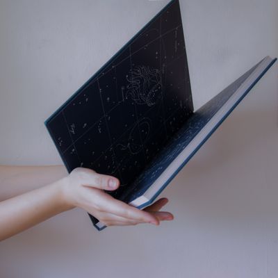 Hands holding an open book of star charts — photo by Alexandra Krainyukhova on Pexels