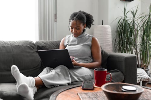 A Woman Using a Laptop While Sitting on a Couch