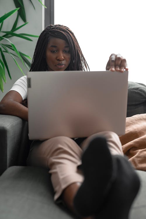 Free A Woman Using a Laptop While Sitting on a Couch Stock Photo