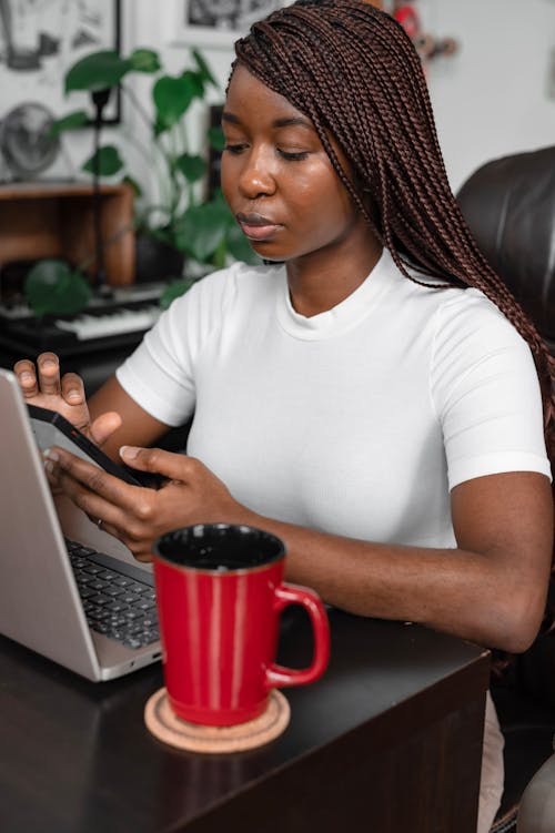 A Woman Using a Cellphone Near a Laptop
