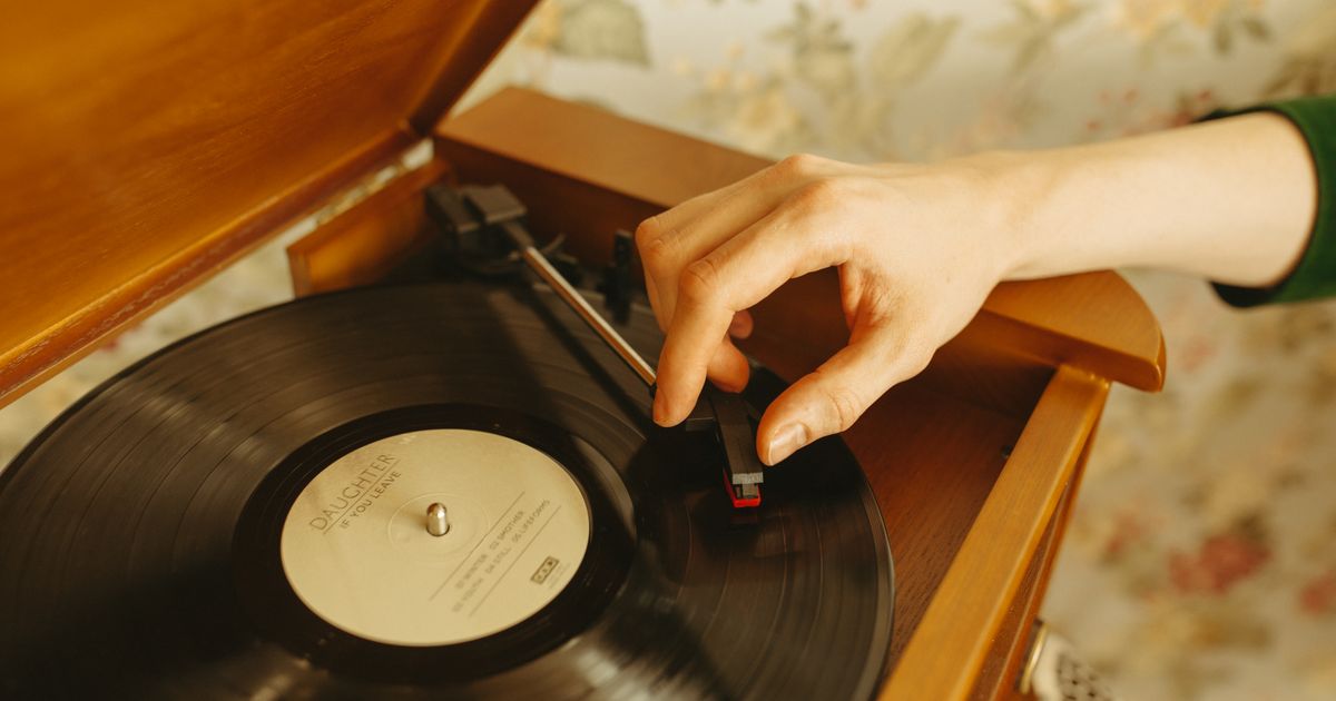 A hand adjusts a needle on a turntable with a retro vinyl record. Nostalgic and vintage vibe.