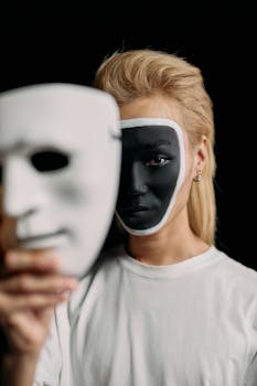 A conceptual portrait featuring creative makeup and a white mask against a black background.