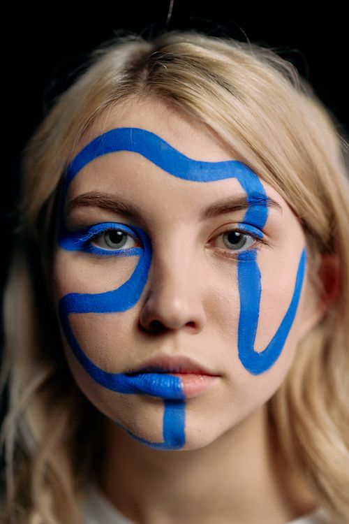 Free Close-up of a woman with abstract, blue face paint on black background. Stock Photo