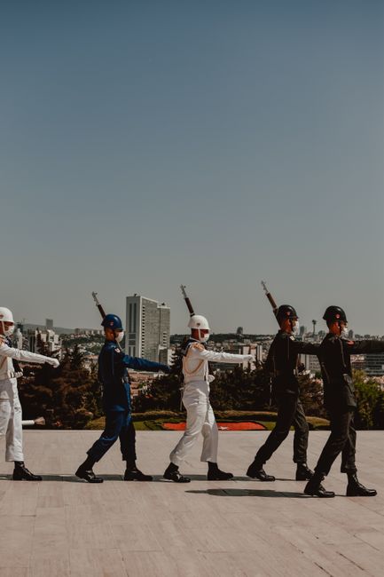 A group of Turkish soldiers in uniform marching at Anıtkabir under a clear sky.
