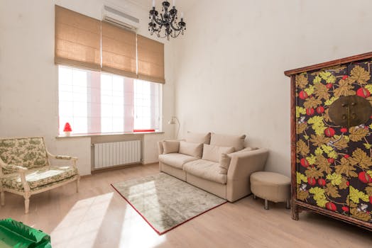 Inviting living room featuring a vintage chair and floral cabinet with abundant natural light.