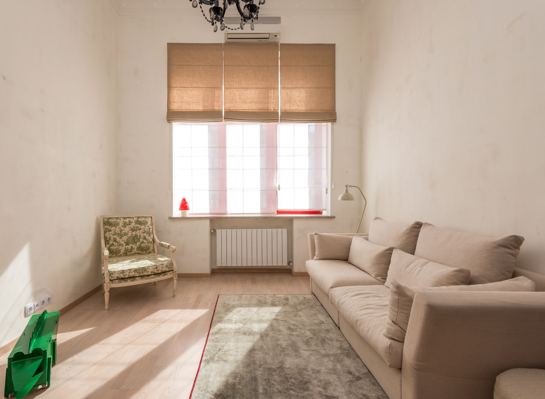 Bright, minimalist living room with beige sofa and classic armchair under warm natural light.