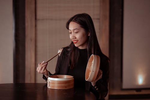 Woman in Black Jacket Holding Chopsticks with Dumplings