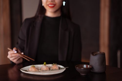 Free Elegant woman dining with dumplings and tea indoors, showcasing traditional Asian cuisine. Stock Photo