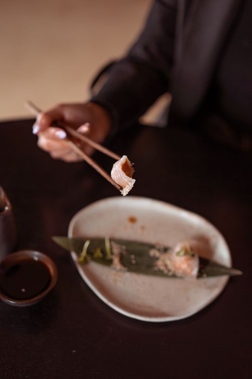 Free Chopsticks holding dumpling over a stylish plate in an upscale dining setting. Stock Photo