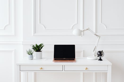A minimalist home office setup featuring a laptop on a white desk with decor items.