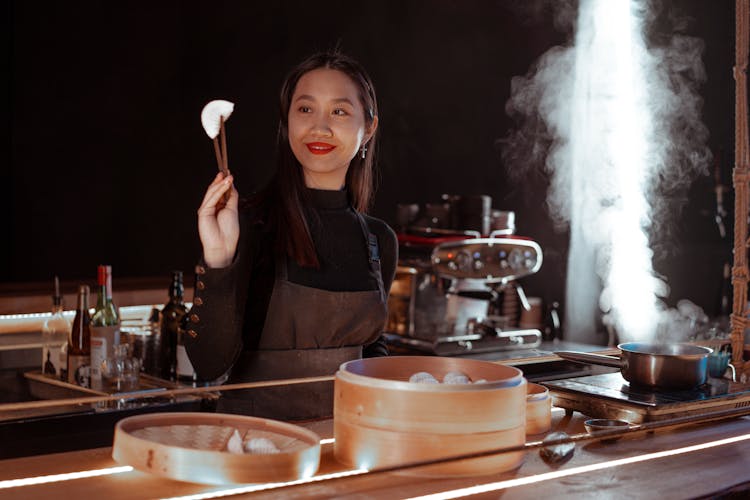 Woman Holding A Dumpling Using Chopstick 