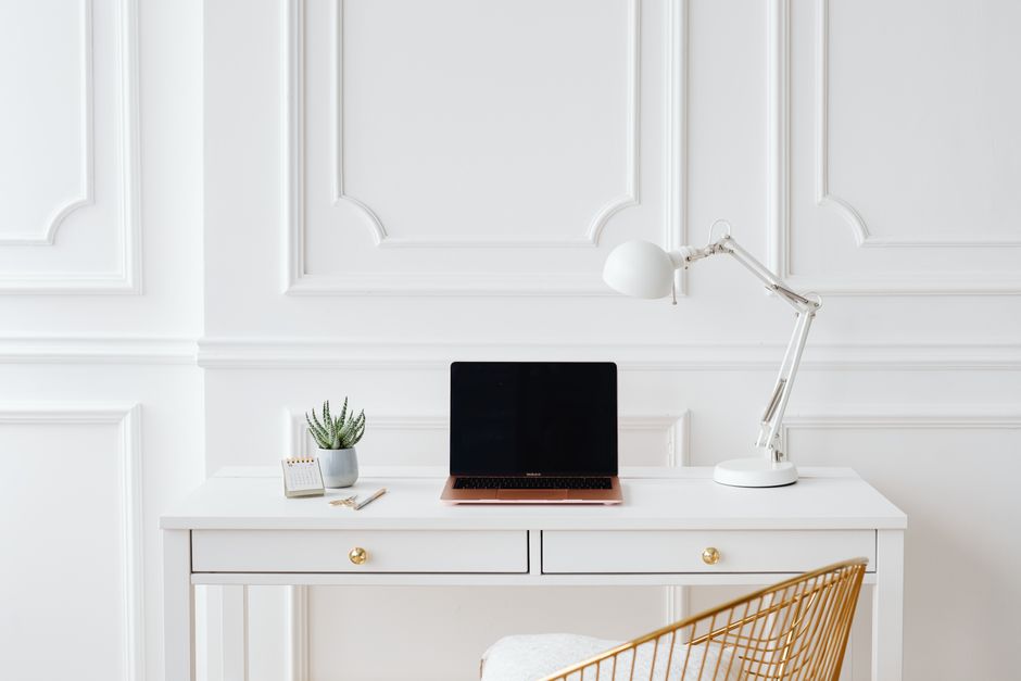 Why Debt Snowball vs Debt Avalanche Debate Misses the Point Elegant minimalist home office desk setup with a laptop, lamp, and indoor plant in a bright white space.